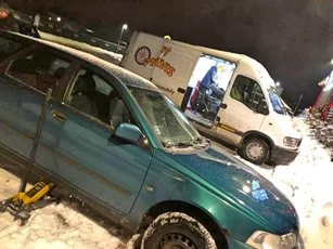 Večerný výjazd v snehu, auto na zdviháku a dodávka s otvorenými dverami